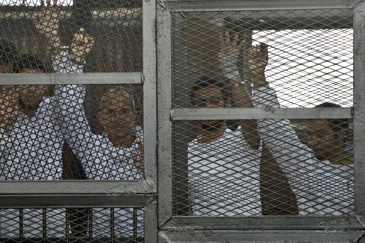 Australian journalist Peter Greste, second from left, of Al Jazeera English and his colleagues stand in the defendants cage at Cairo's Tora prison during their trial for allegedly supporting the Muslim Brotherhood on March 5, 2014.