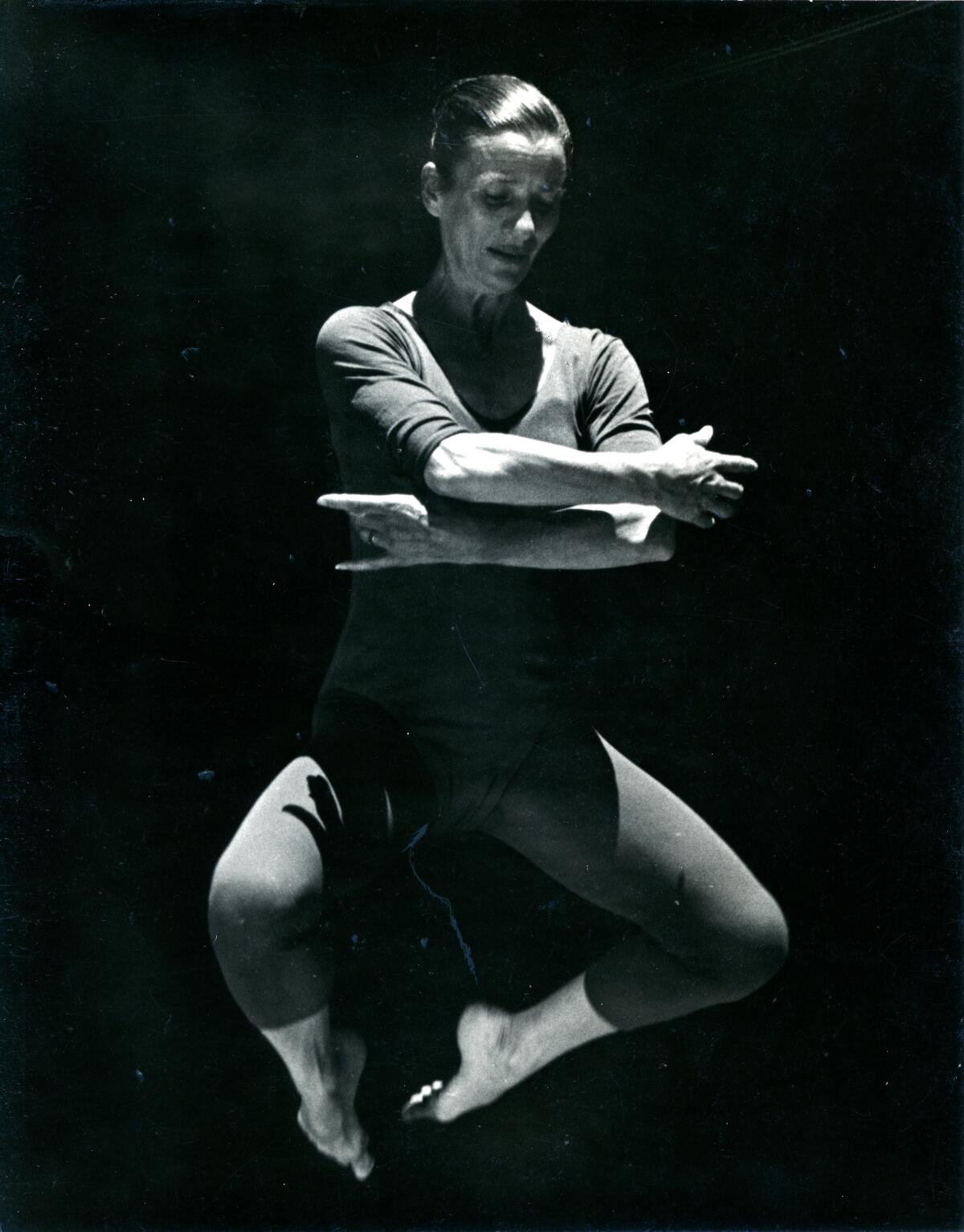 A woman mid-leap, folding her legs under her.