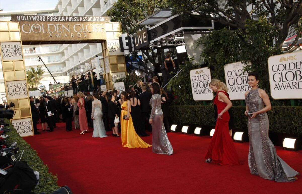 A line of people in formal wear on the red carpet at the Golden Globe Awards