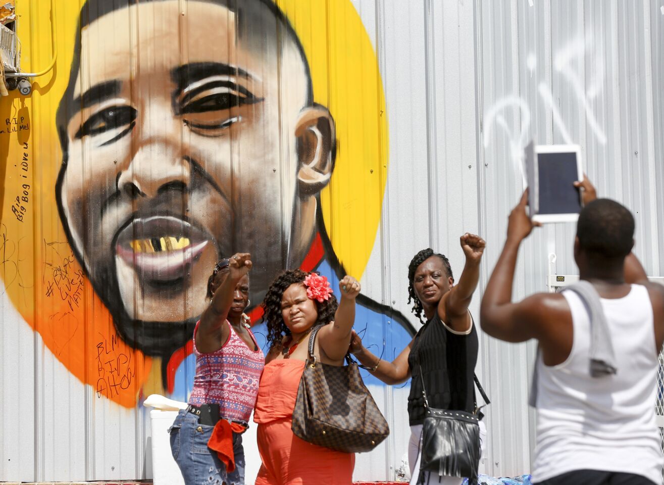 Baton Rouge, La., residents take photos with their fists raised in front of a mural of Alton Sterling, who was killed by police in early July.