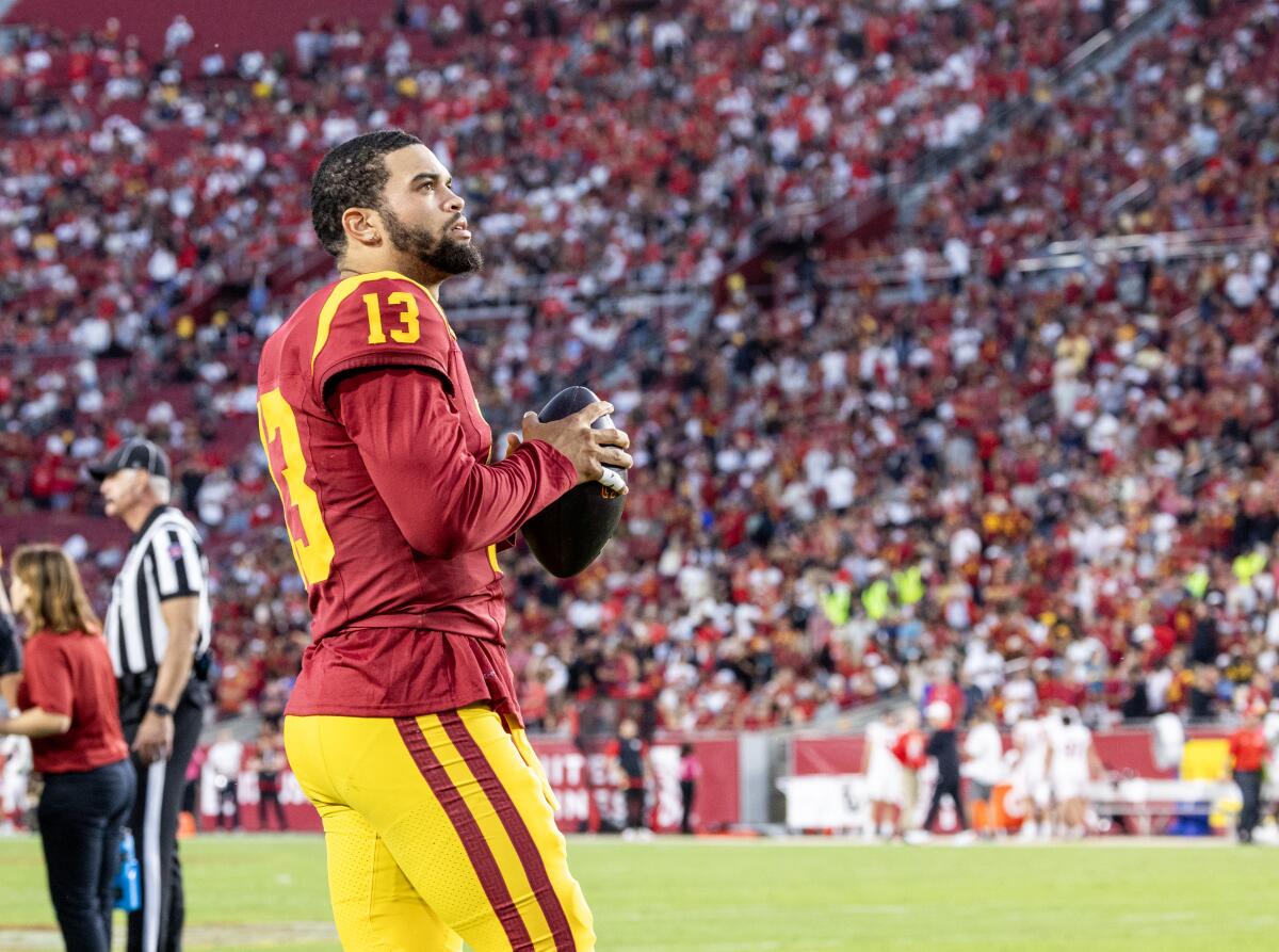 USC quarterback Caleb Williams looks up while holding a football.