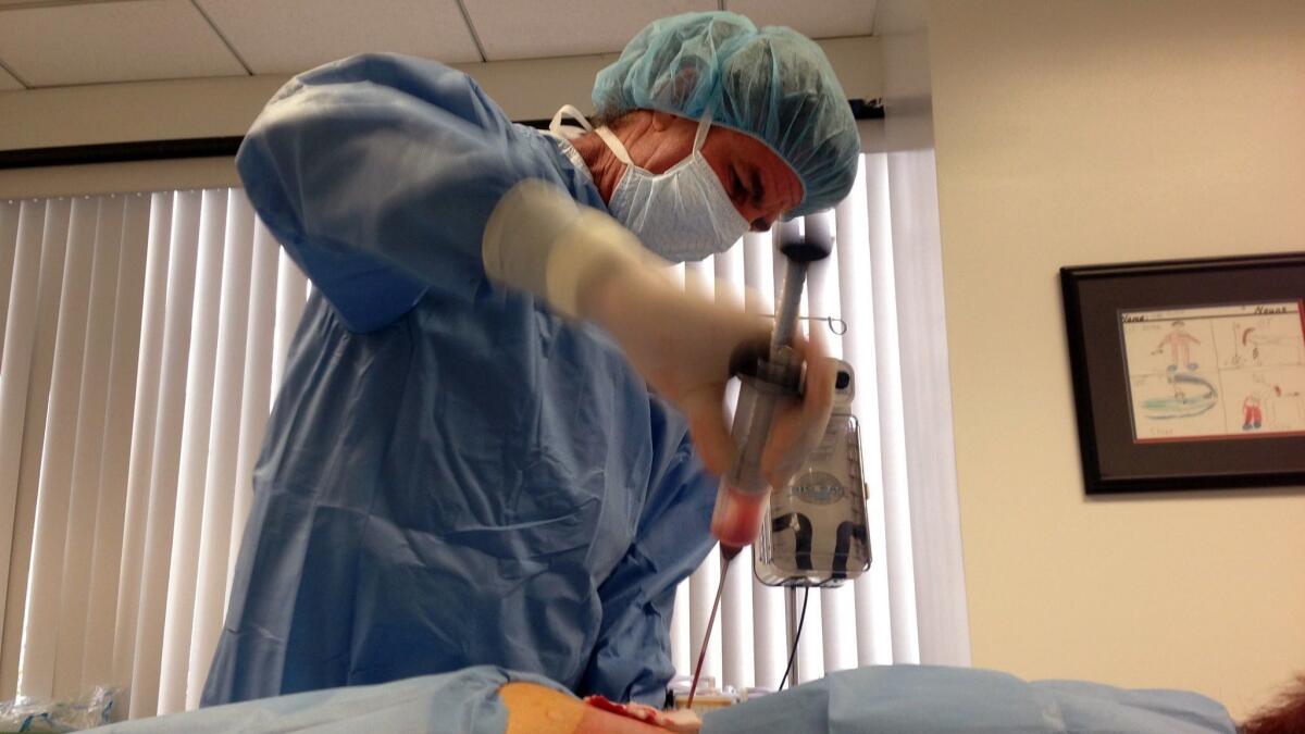 A doctor collects fat from a patient's back as part of an experimental stem cell procedure in Beverly Hills, Calif. on Dec. 5, 2014.