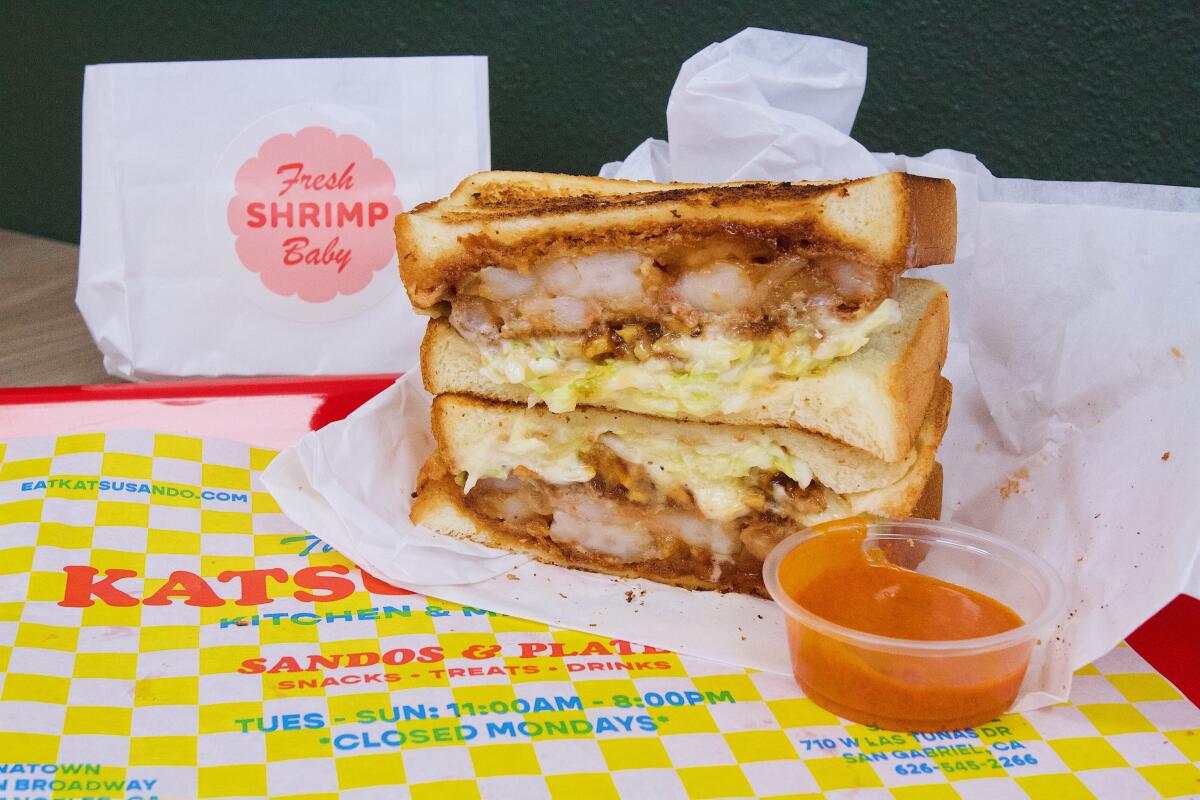 A horizontal photo of the shrimp walnut katsu sando on a red tray with yellow-and-white checkered paper. 