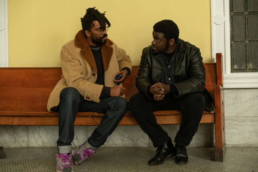 Director Shaka King, left, and Daniel Kaluuya sit on a bench.