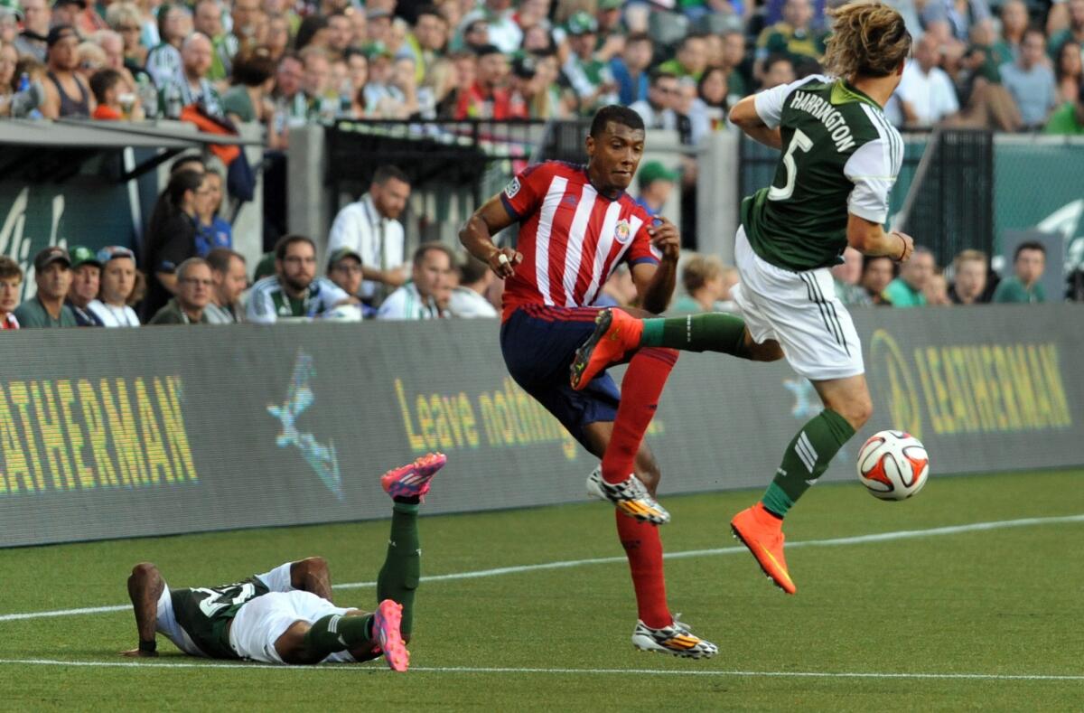 Chivas USA's Oswaldo Minda, center, goes after the ball wit Portland's Michael Harrington during the first half of a game on Saturday. Chivas USA lost to the Timbers, 2-0.