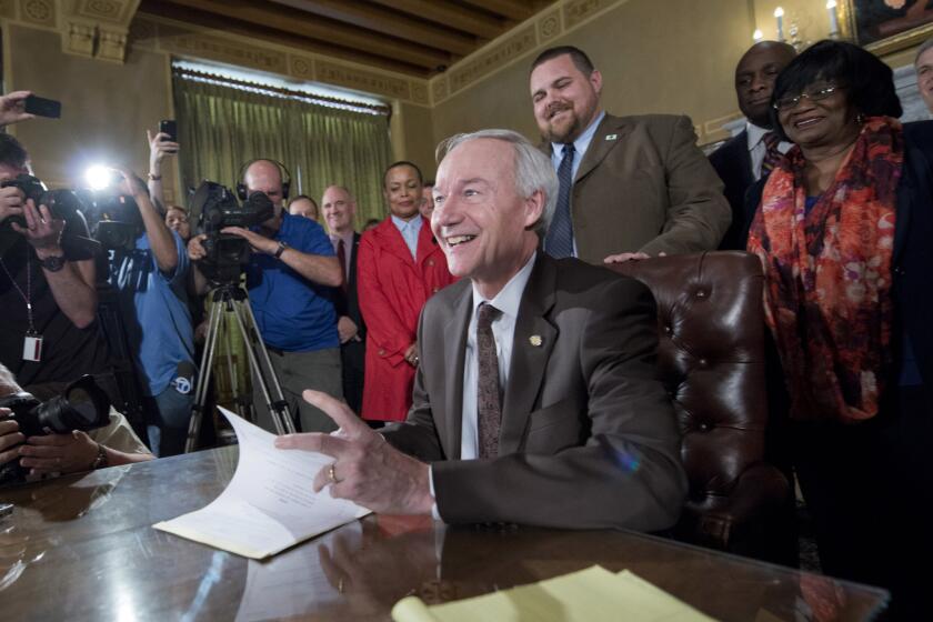 Arkansas Gov. Asa Hutchinson signs a reworked religious freedom bill into law after it passed in the House at the Arkansas state Capitol in Little Rock, Ark., Thursday, April 2, 2015. Lawmakers in Arkansas and Indiana passed legislation Thursday that they hoped would quiet the national uproar over new religious objections laws that opponents say are designed to offer a legal defense for anti-gay discrimination. (AP Photo/Brian Chilson) ORG XMIT: ARDJ110