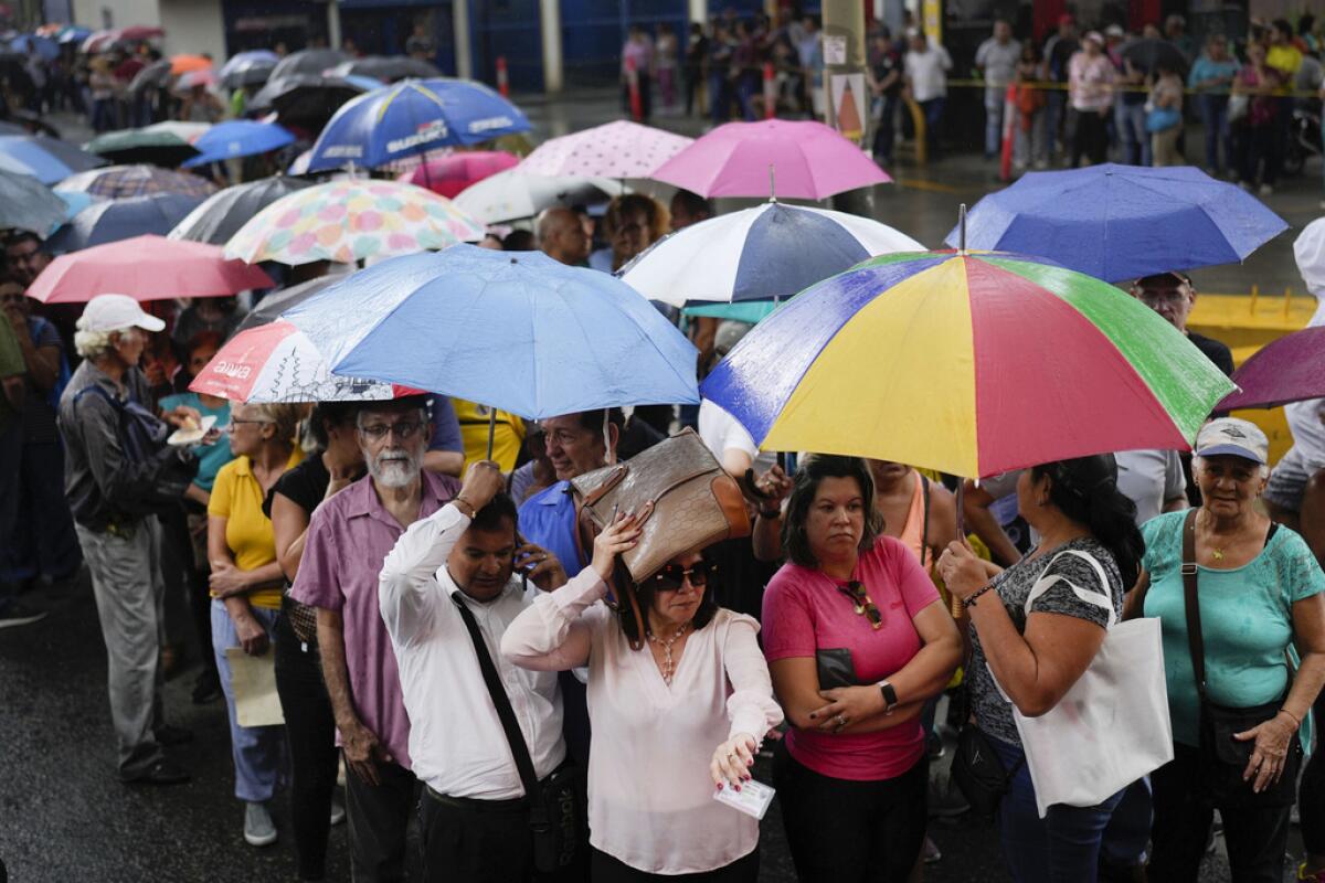 Personas hacen fila en medio de una fuerte lluvia para votar