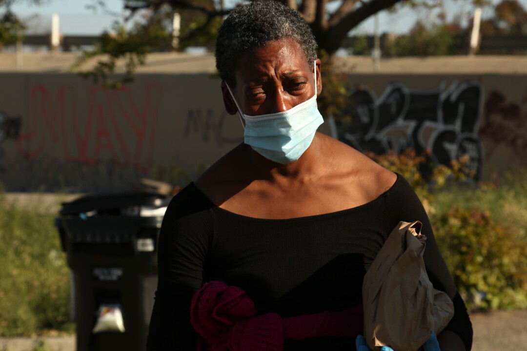 A fatigued homeless woman carries a bag lunch provided by Gernay Quinnie Jr.