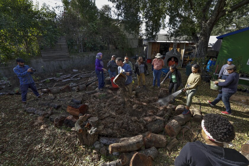 Shawn Maestretti and Leigh Adams lead workshop attendees in adding another layer of carbon on the combination lasagna mulching and berms in his backyard.