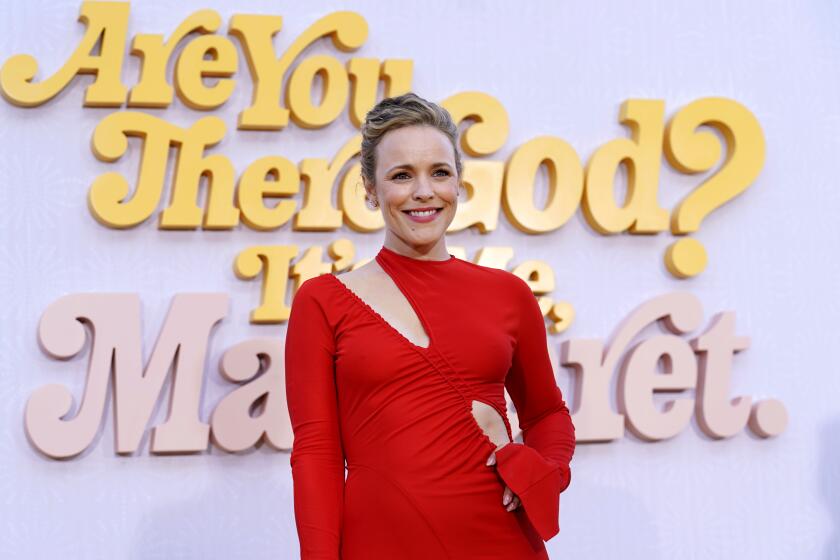 Rachel McAdams smiles in a red dress at a movie premiere.
