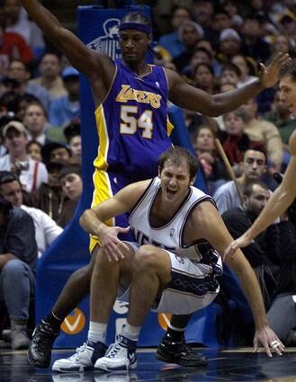 New Jersey Nets' Nenad Krstic goes down after injuring his knee as he is guarded by Lakers' Kwame Brown.