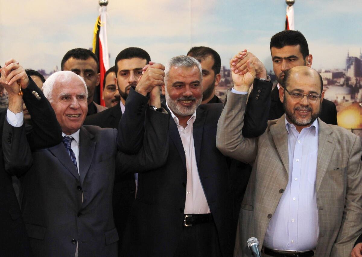 Palestinian Fatah delegation chief Azzam Ahmed, left, Hamas Prime Minister in the Gaza Strip Ismail Haniya and Hamas deputy leader Musa abu Marzuk pose for a photo as they celebrate the Palestinian unity accord Wednesday in Gaza City.