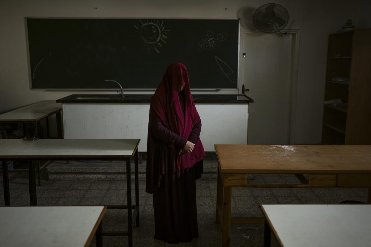 A woman, her head covered, stands in a classroom.