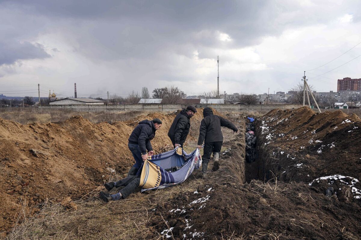 Dead bodies are put into a mass grave on the outskirts of Mariupol, Ukraine 