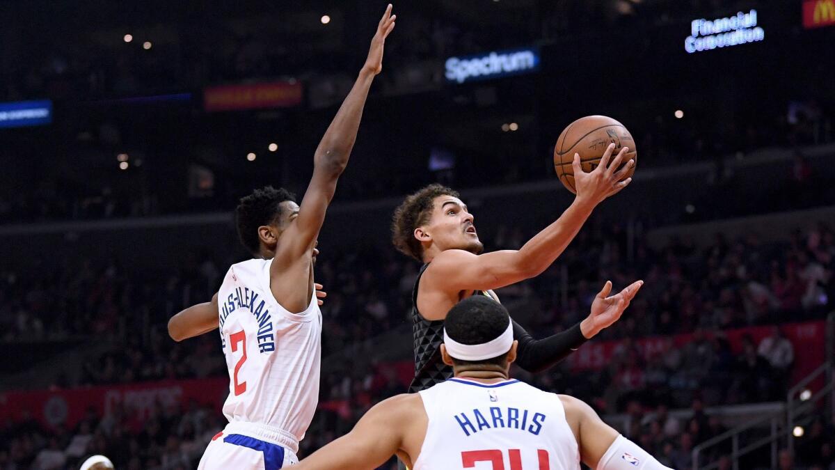 Trae Young (11) of the Atlanta Hawks scores on a layup against Shai Gilgeous-Alexander (2) and Tobias Harris (34) of the Clippers during the first half.