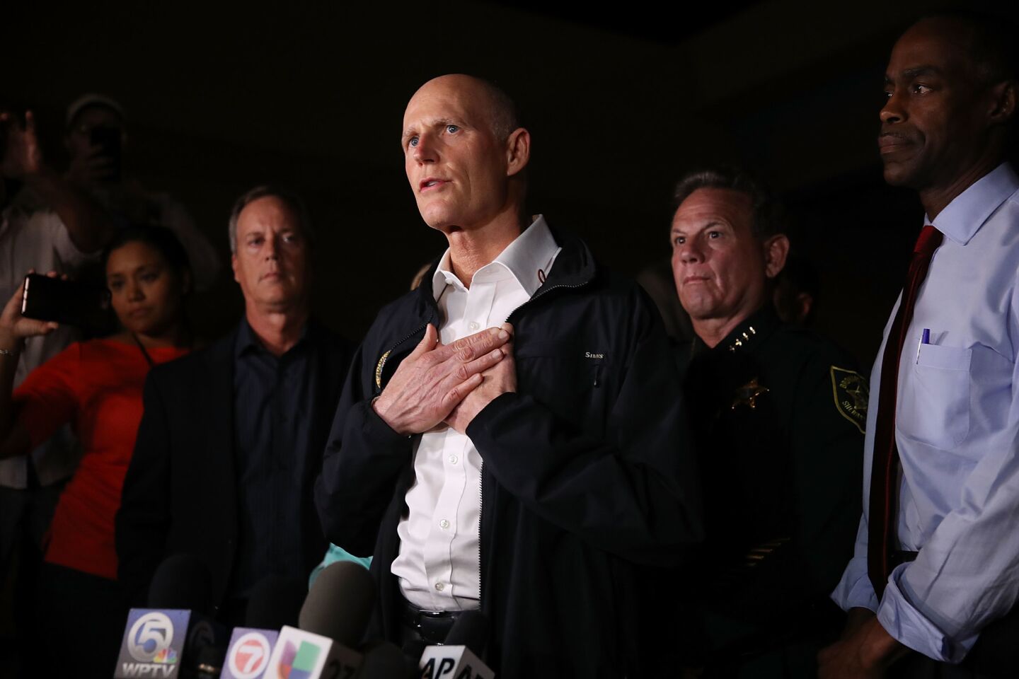 Florida Gov. Rick Scott speaks to the media as he visits Marjory Stoneman Douglas High School in Parkland, Fla., after a shooting there killed 17 people.