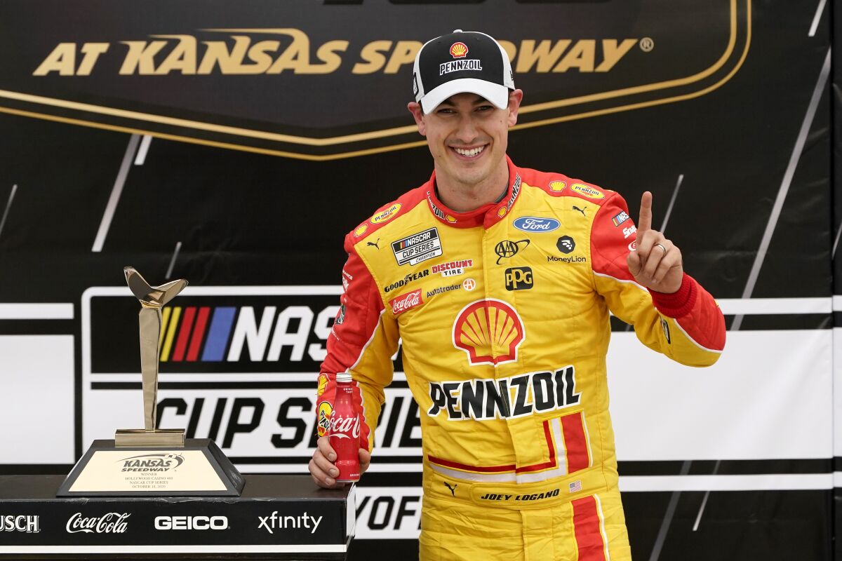 Joey Logano celebrates in victory lane after winning a NASCAR Cup Series auto race at Kansas Speedway.