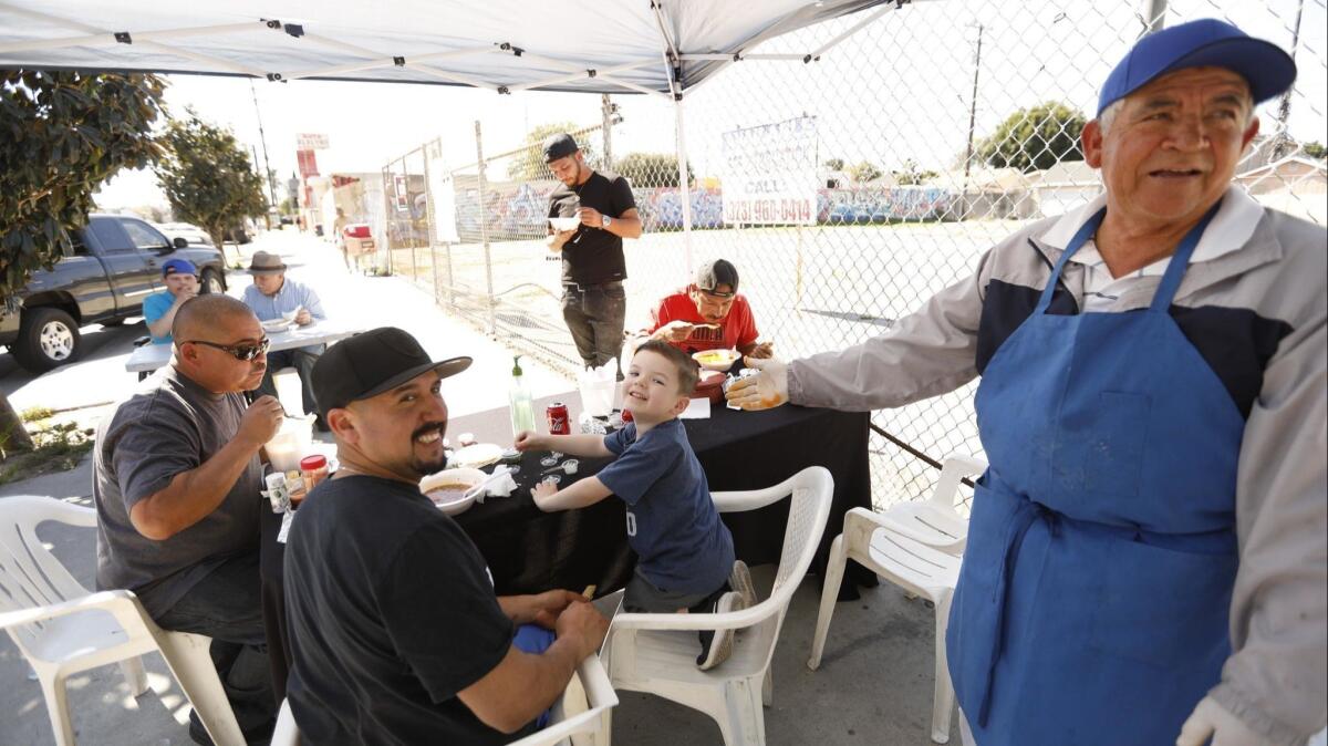 Joel Mendez, right, enjoys a light moment with customers at his Mr. Menudo pop-up stand.