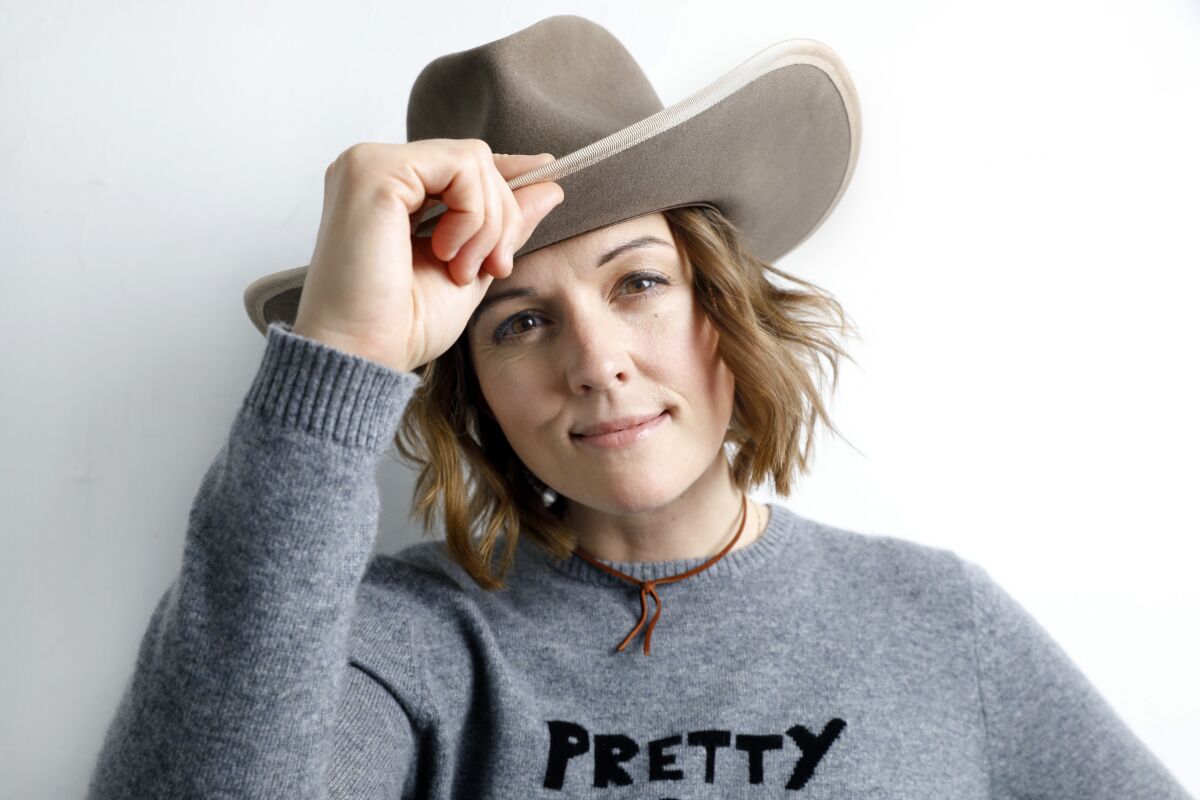A woman in a gray sweater and a cowboy hat
