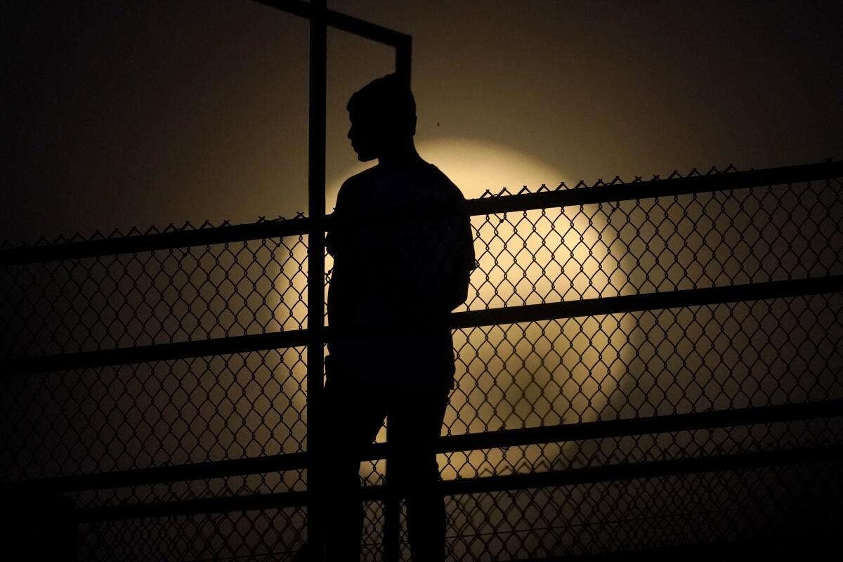 A person stands on an observation tower as the moon rises in New Albany, Ind. 