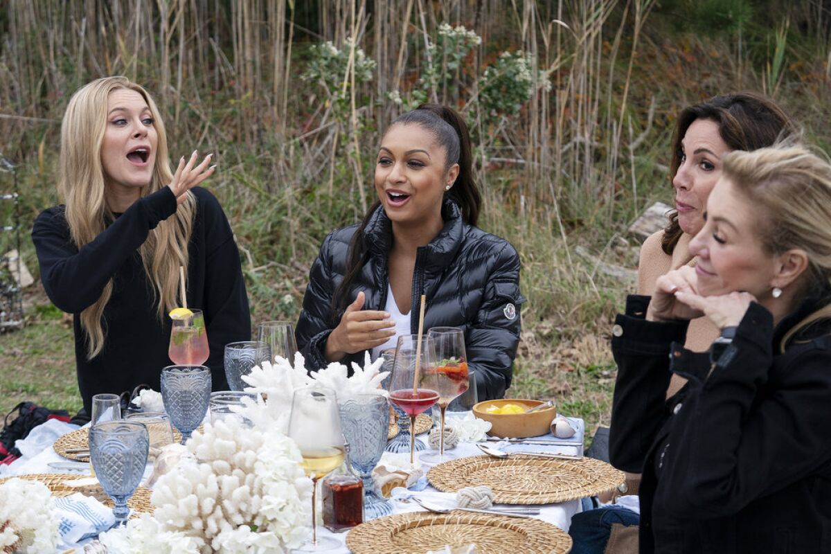 A group of women drinking and conversing around an outdoor table 