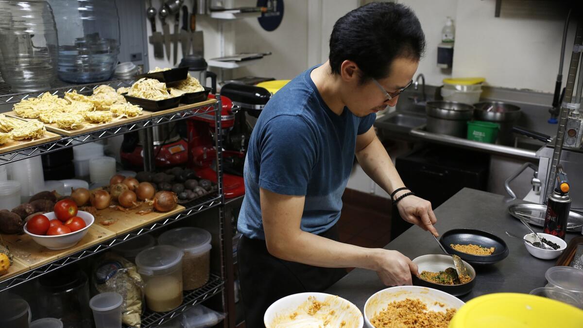 Chef Kwang Uh, shown preparing a meal in his restaurant Baroo, is an accomplished chef who has opened up his own restaurant in a Los Angeles strip mall.