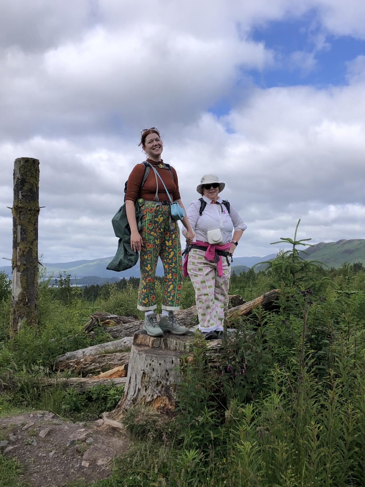 Two women pose in hiking gear along a trail in Scotland.