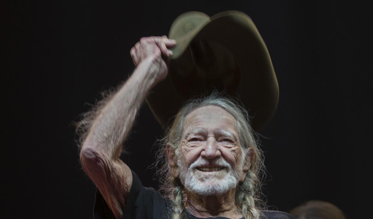 Country music legend Willie Nelson tips his hat to the crowd