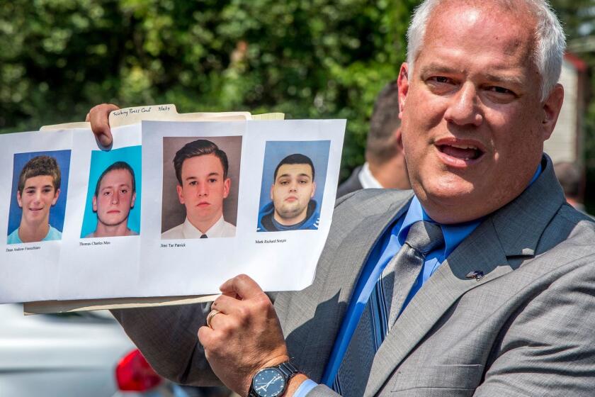 Bucks County District Attorney Matthew Weintraub holds up photos of four men who are missing during a news conference in Solebury Township, Pa., Monday, July 10, 2017. The four men, who went missing last week, are Dean Finocchiaro, from left, Tom Meo, Jimi Tar Patrick and Mark Sturgis. (Clem Murray/The Philadelphia Inquirer via AP)