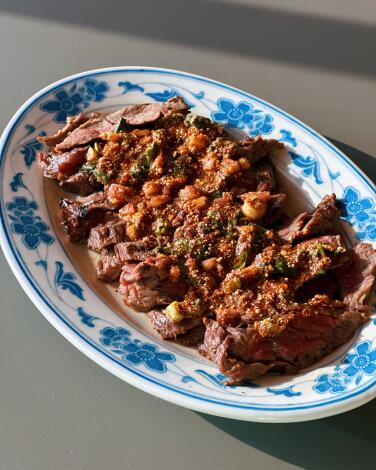  Charcoal-grilled rib-eye steak marinated in Thai herbs and spices on a blue and white oval platter