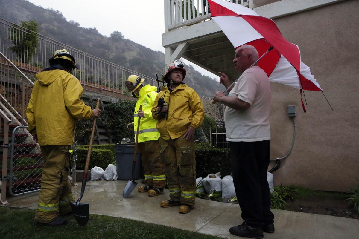 Ed Heinlein, right, talks to Los Angeles County Fire Department crew members about landslide dangers behind his home and how he has prepared to face the danger in Azusa that is under mandatory evacuation orders.