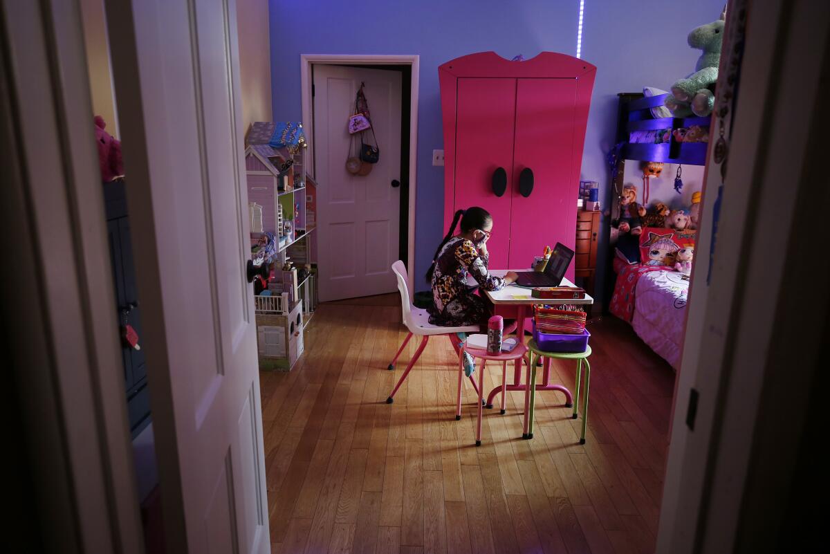 A nine-year-old girl attends online class in her bedroom