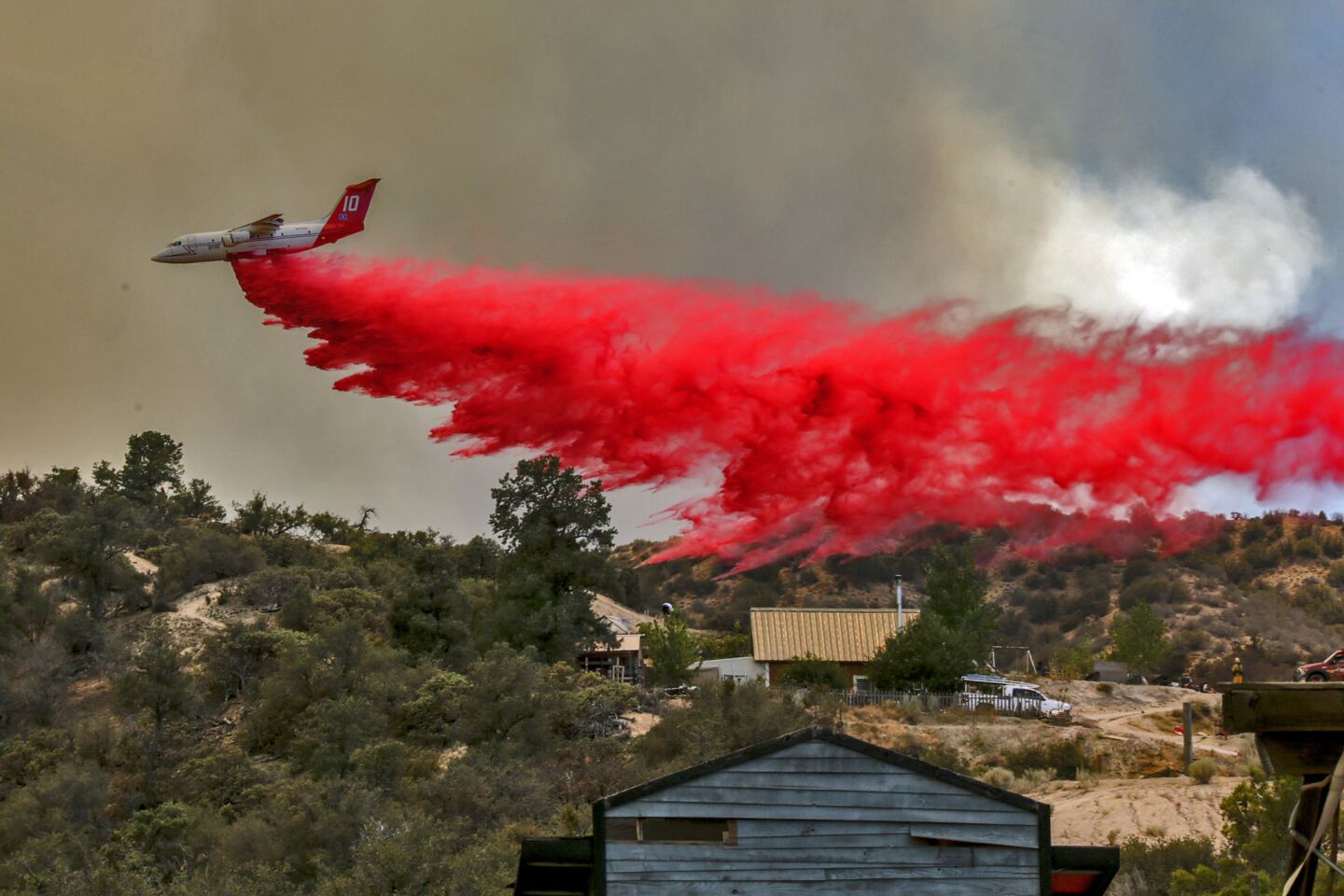 Air tanker drops fire retardant near residences threatened by Blue Cut Fire along Highway 2 Wednesday afternoon.