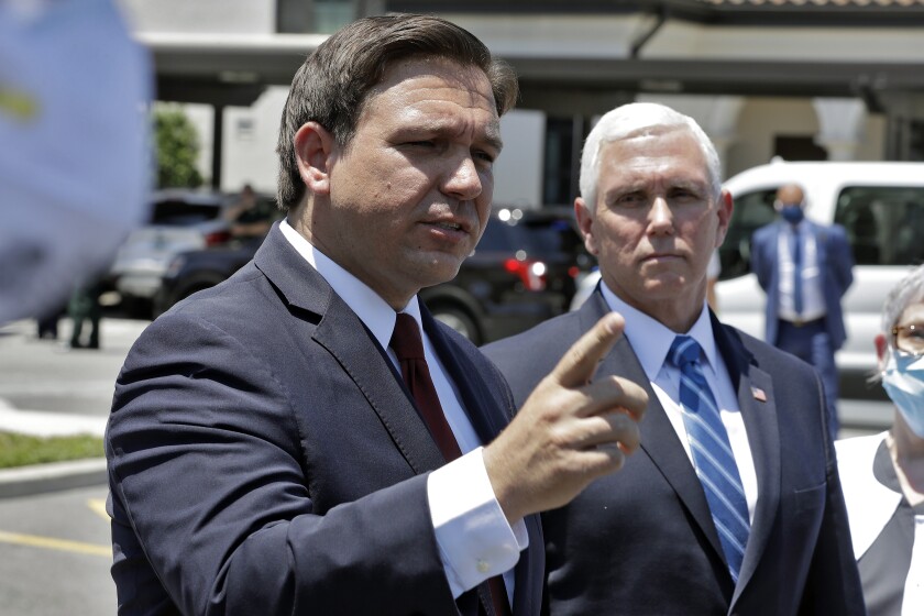 Florida Gov. Ron DeSantis, left, speaks to the media with Vice President Mike Pence in Orlando, Fla., on Wednesday.