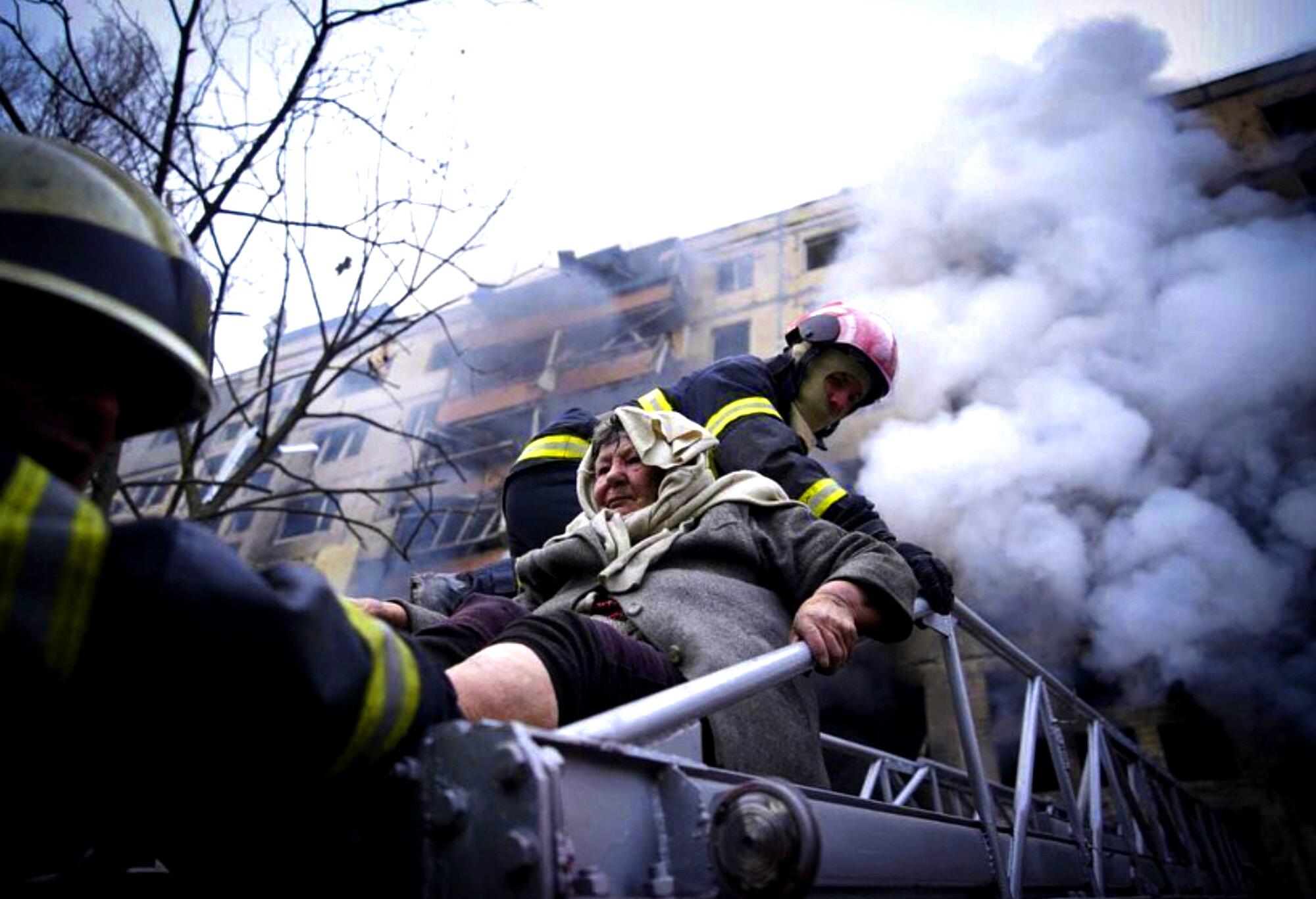 Firefighters evacuate an elderly woman from an apartment building hit by shelling in Kyiv.