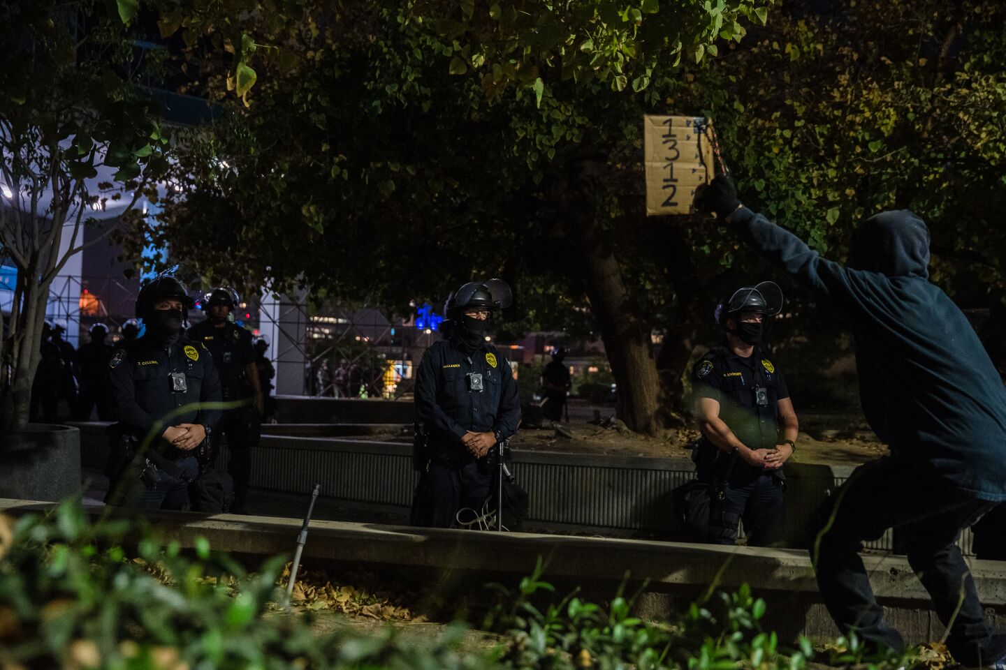 A protester waves a sign in front of police officers after protesters pushed down a barricade at the San Diego Police Department headquarters on September 23, 2020.