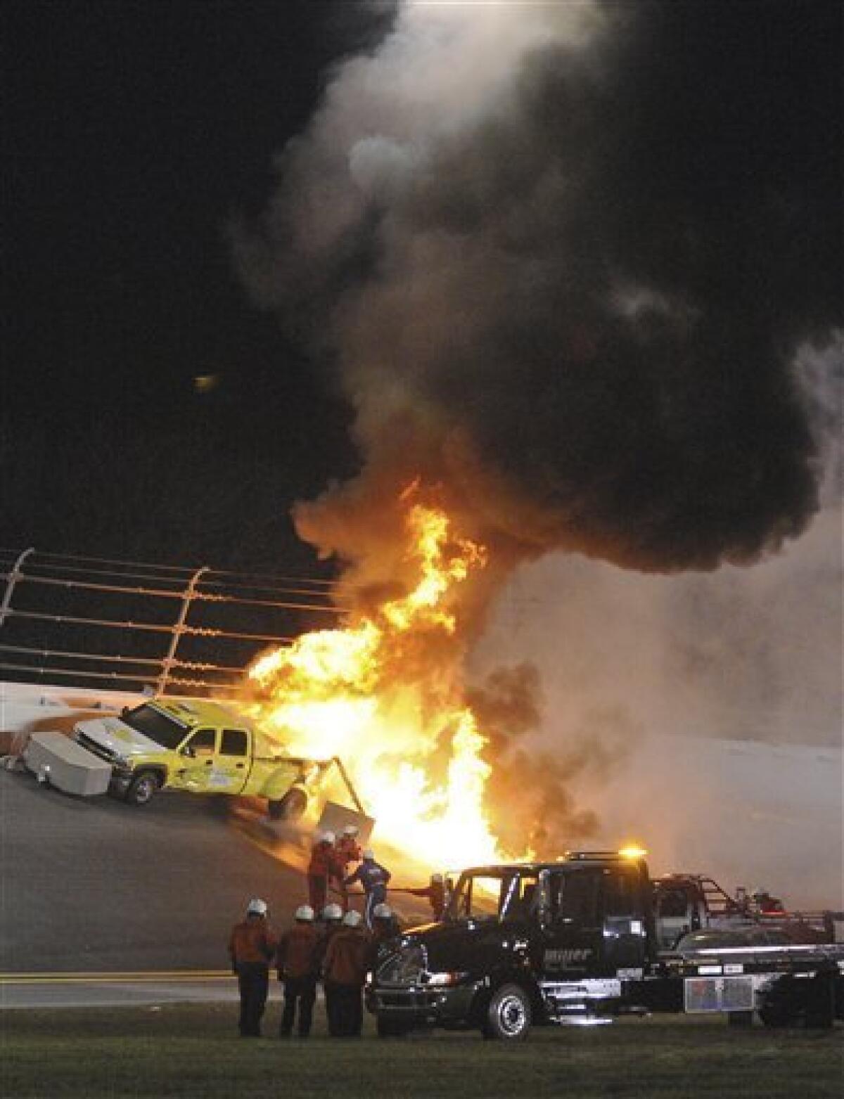 Emergency workers try to extinguish a fire on a jet dryer during the NASCAR Daytona 500 auto race at Daytona International Speedway in Daytona Beach, Fla., Monday, Feb. 27, 2012. Juan Pablo Montoya's car struck the dryer during a caution period after something on his car broke. (AP Photo/Rob Sweeten)