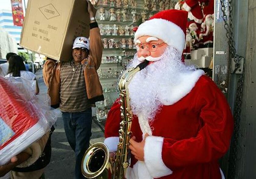 A man carrying a box on his shoulder walks by a figure of Santa Claus playing the saxophone.