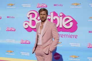 Ryan Gosling squints in the sunlight while wearing a pale pink suit at a movie premiere