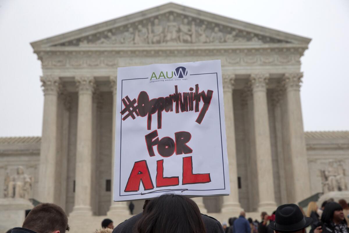 People hold a sign that says "#OpportunityForAll" in front of the Supreme Court