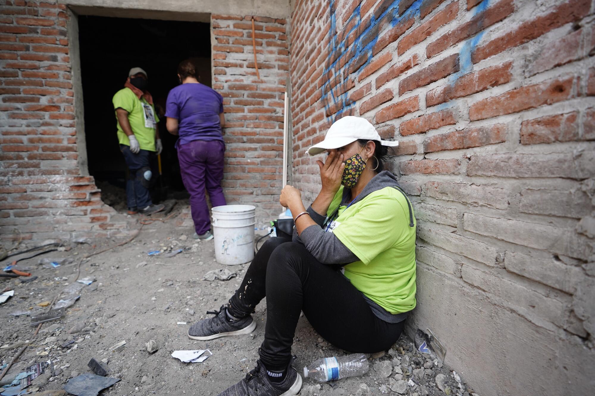 Barbara Martinez is emotional as she sits on the ground against a wall.