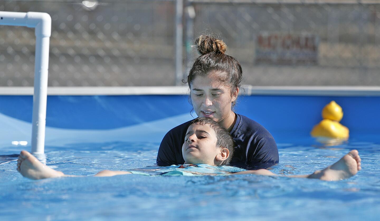 Mason Tarvirdian, 6, of Tujunga, with guidance from swim instructor Maryjane Martinez, of La Crescenta, practices floating on his back in a YMCA of the Foothills program to teach small children about water safety in a portable swimming pool at Sunland Elementary School on Tuesday, July 3, 2018. The pool, with a depth of 3'8" was the idea of Venus Payandeh, of the YMCA of the Foothills, and will be in place teaching small children how to save themselves until August 6.