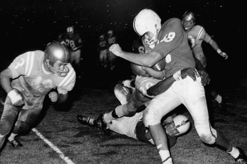 Roman Gabriel, North Carolina State quarterback, is in the clutches of one UCLA player.