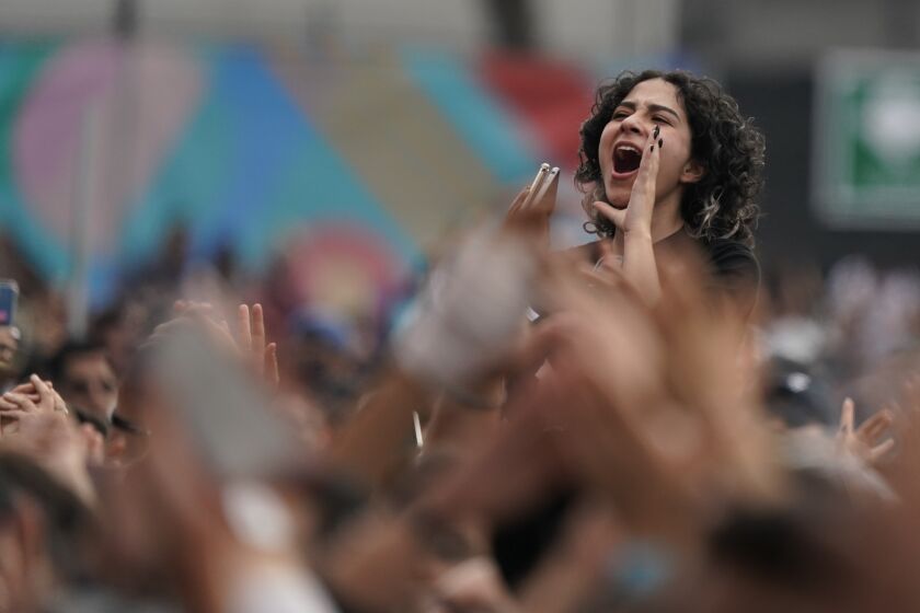 FILE - A fan cheers during the 22th edition of the Vive Latino music festival in Mexico City, Sunday, March 20, 2022. The Vive Latino Festival has become Latin America's biggest Latin rock celebration. As coronavirus cases increase during 2022 in places like China, where authorities are implementing a new round of lockdowns, Latin American countries are eliminating restrictions on mass gatherings and stopping mask mandates that have lasted for two years. (AP Photo/Eduardo Verdugo, File)