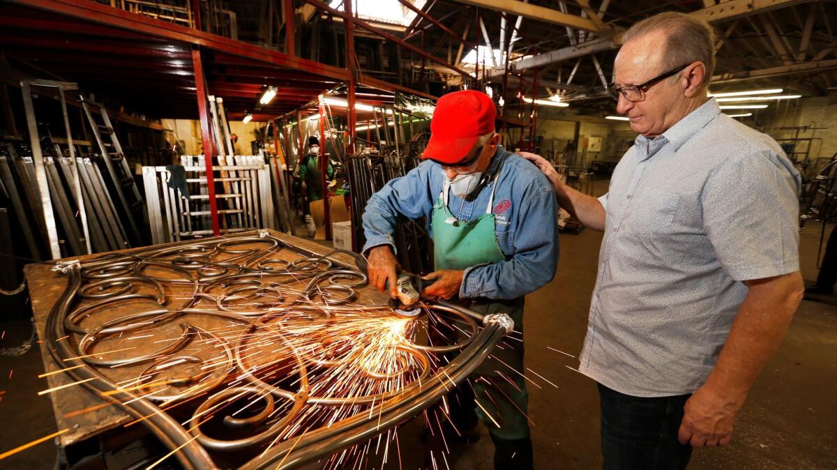 Victor Sawan, right, with Mauricio Silva, who is grinding a bed frame at the Wesley Allen factory.