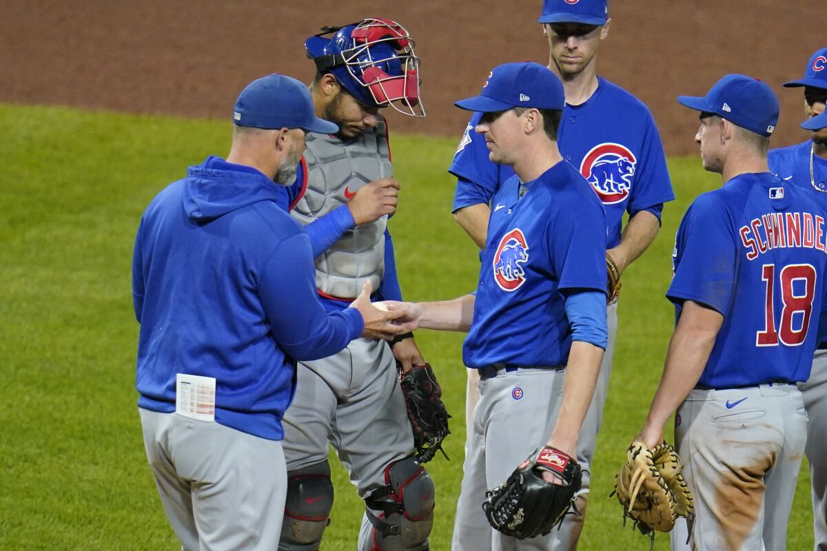 Chicago Cubs starting pitcher Kyle Hendricks, center, hands the ball to manager David Ross, left, as he leaves the baseball game in the sixth inning against the Pittsburgh Pirates in Pittsburgh, Wednesday, Sept. 29, 2021. (AP Photo/Gene J. Puskar)