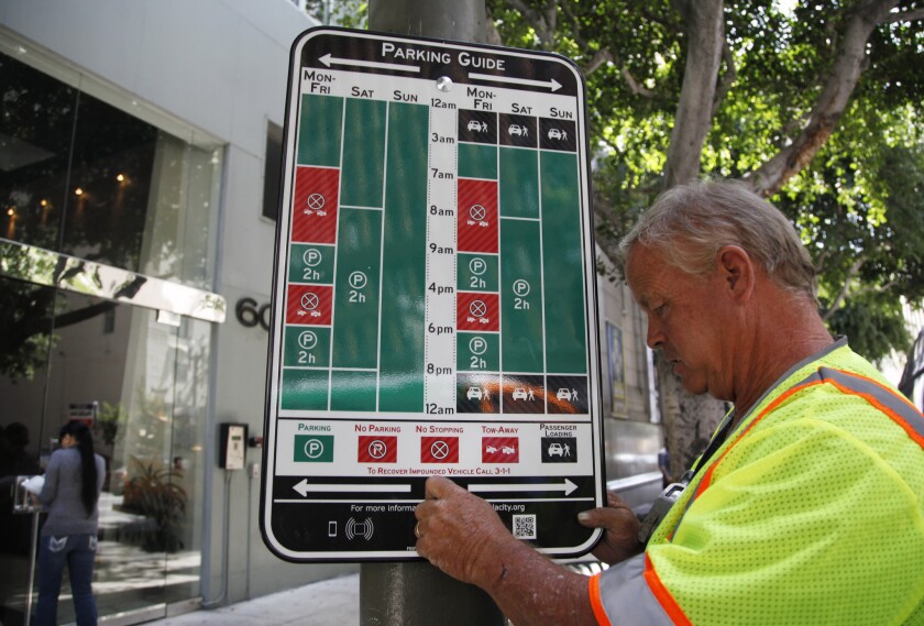Transportation Department employee Doug Aitken hangs a redesigned sign designed to reduce confusion over parking regulations.
