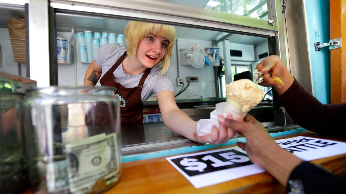 Caitlyn Faircloth, a worker with Molly Moon's Homemade Ice Cream, hands out free ice cream next to a tip jar, Monday, June 2, 2014, at a rally outside City Hall in Seattle celebrating the Seattle City Council's approval of a $15 minimum wage.
