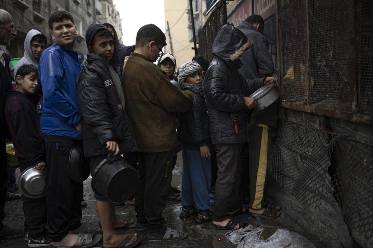 Niños palestinos esperan en una fila para recibir comida