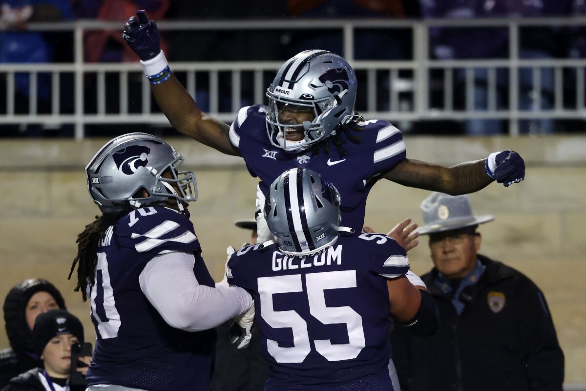 Kansas State wide receiver Malik Knowles, top, celebrates with linemen KT Leveston (70) and Hayden Gillum (55) after scoring a touchdown during the first quarter of the team's NCAA college football game against Kansas on Saturday, Nov. 26, 2022, in Manhattan, Kan. (AP Photo/Colin E. Braley)